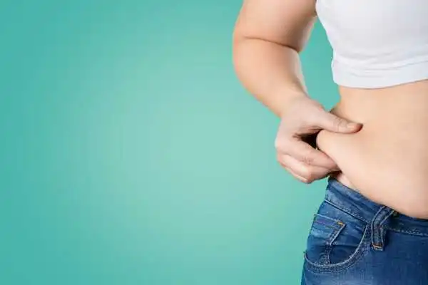 Image of woman pinching her love handles to show weight gain Abingdon