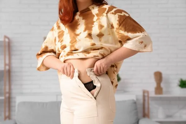 Image of woman trying to do her trousers up after pregnancy weight gain Abingdon