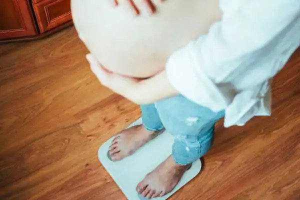 Image of woman weighing herself and experiencing weight gain through pregnancy Abingdon